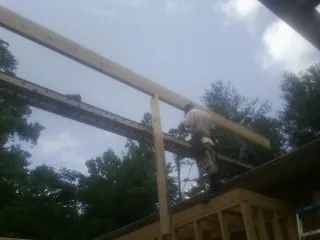 Carpenter setting a ridge beam over a new addition frame — Ice Dam Removal by Roofing Brothers in Cherry Plain