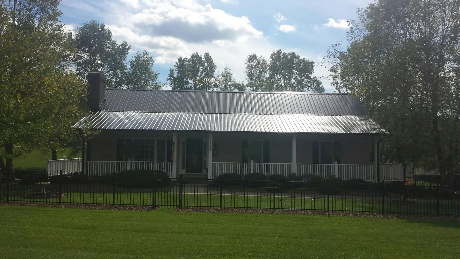 Gray metal roof on a brick ranch with a full width front porch — Gutter Guard Installation work by our crew in Cherry Plain