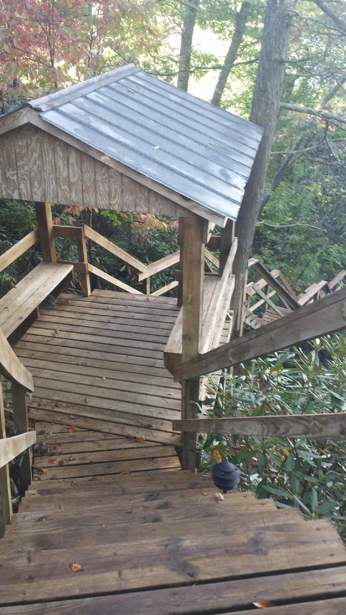Metal roofed shelter over wooden steps on a wooded walkway — Skylight Repair & Installation work by our crew in Cherry Plain