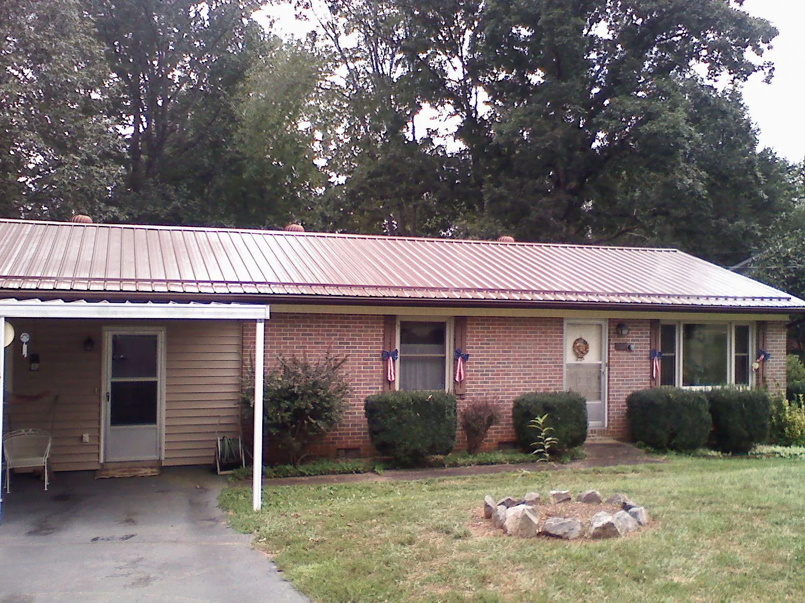 Bronze metal roof and carport on a brick ranch home — Roof Repair work by our crew in Cherry Plain
